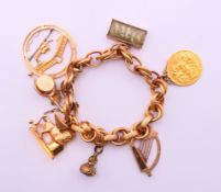 An unmarked, probably 9 ct gold, charm bracelet set with various charms including a 1915 sovereign.