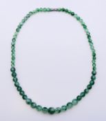A string of two-tone jade beads. 47 cm long.