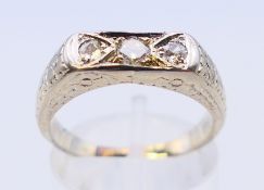 An 18 ct white gold three-stone diamond ring. Ring size O.