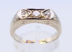 An 18 ct white gold three-stone diamond ring. Ring size O.