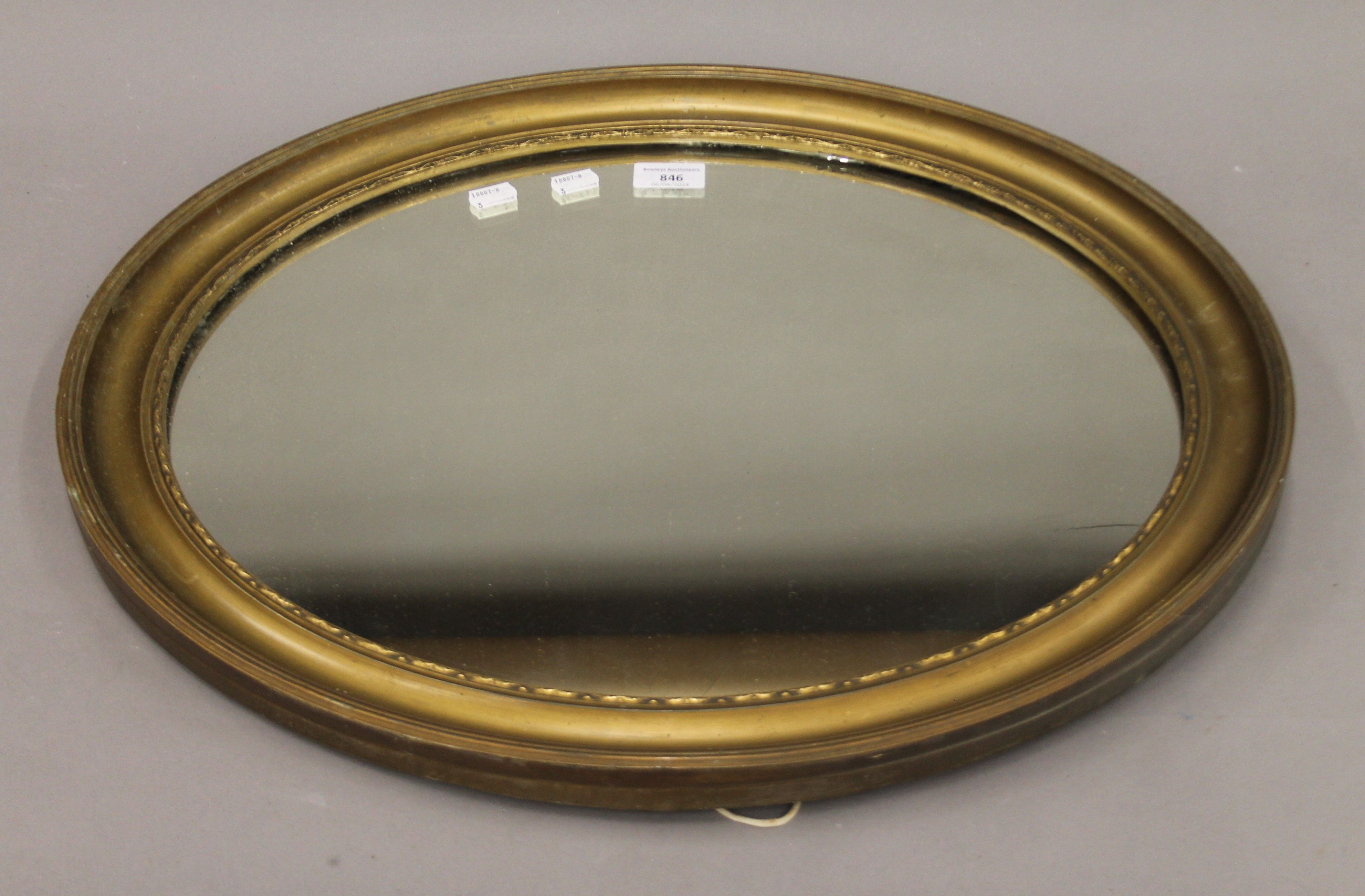 An early 20th century gilt-framed oval mirror. 58 cm wide.