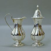 A silver cream jug and a silver sugar caster. The latter 18 cm high. 300.9 grammes.