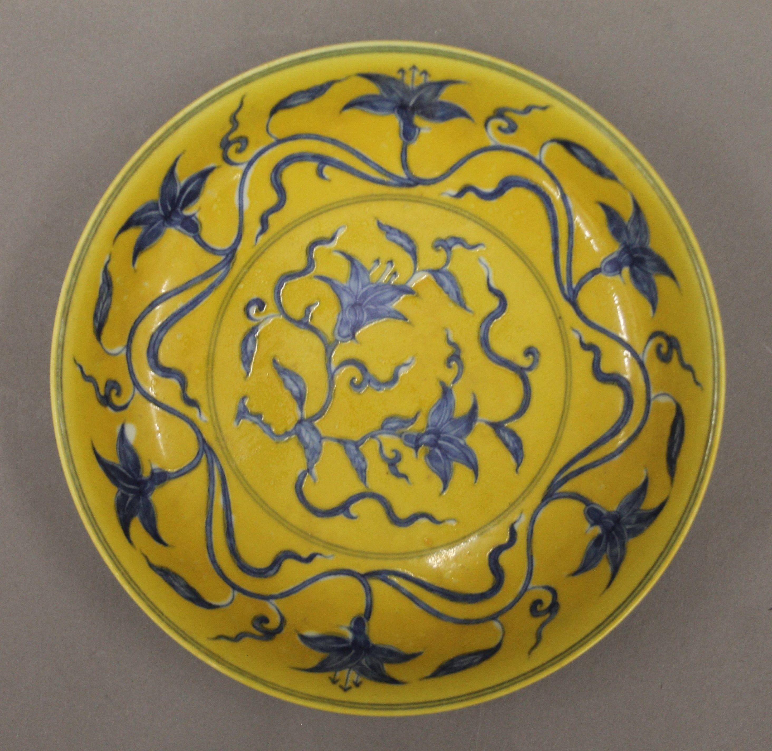 A Chinese yellow ground porcelain dish decorated with blue trailing foliage. 20.5 cm diameter. - Image 2 of 4