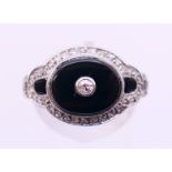 A platinum, black onyx and diamond ring. Ring size N/O.