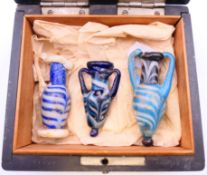 Three Roman glass vessels in a wood presentation box. The largest 6.5 cm.