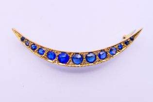 A 9 ct gold, sapphire and diamond crescent brooch. 5 cm high. 2.9 grammes total weight.