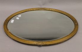 A gilt-framed bevelled oval wall glass/mirror. 66 cm wide.