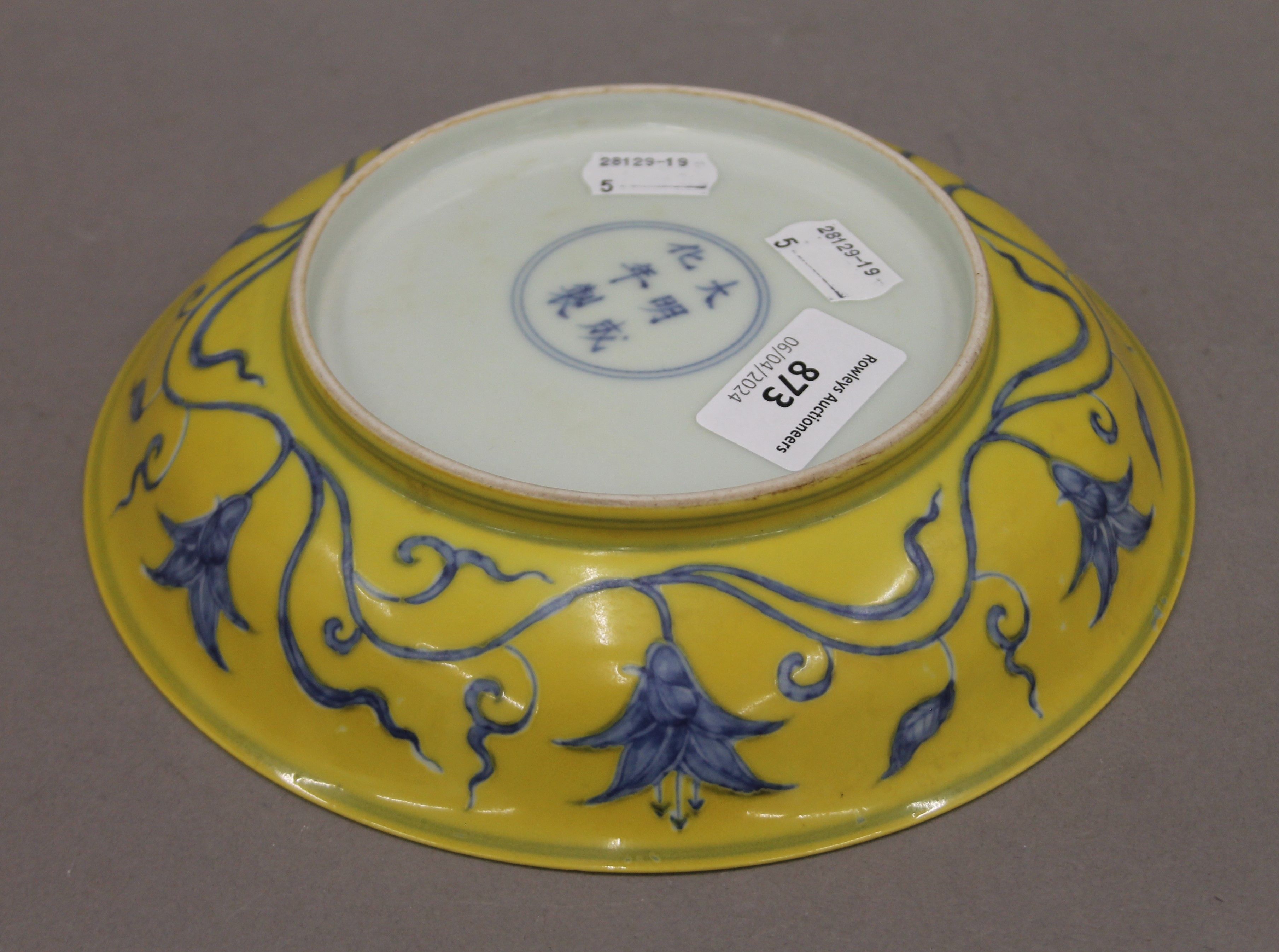 A Chinese yellow ground porcelain dish decorated with blue trailing foliage. 20.5 cm diameter. - Image 4 of 4