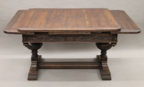 An early 20th century carved oak drawer leaf dining table. 193 cm long extended x 99 cm wide.