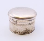 A small silver pill box. 2.5 cm diameter.
