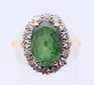 An 18 ct gold and oval tourmaline and diamond cluster ring, the tourmaline (11.3 x 7.8 x 4.
