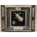 A boxed and framed Saudi Arabian silver coffee pot. The box 30 cm wide.