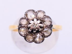 An 18 ct gold diamond daisy-head ring. Ring size O/P.