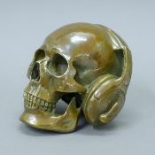 A bronze skull wearing headphones. 19 cm wide.