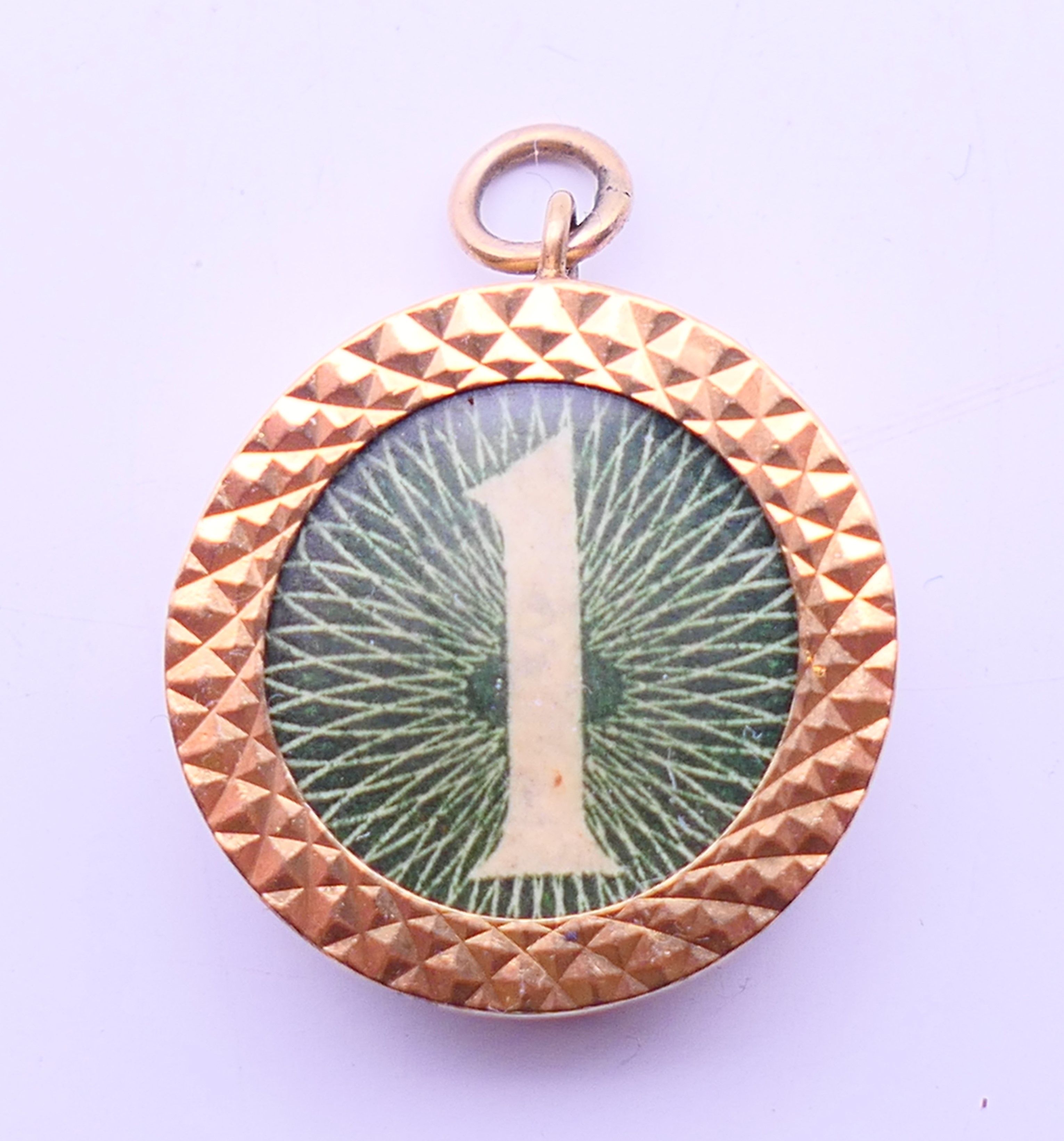 A 9 ct gold £1 note charm. 2 cm diameter.