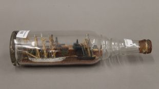 A vintage ship in a bottle set with a townscape and a young boy. 29.5 cm long.