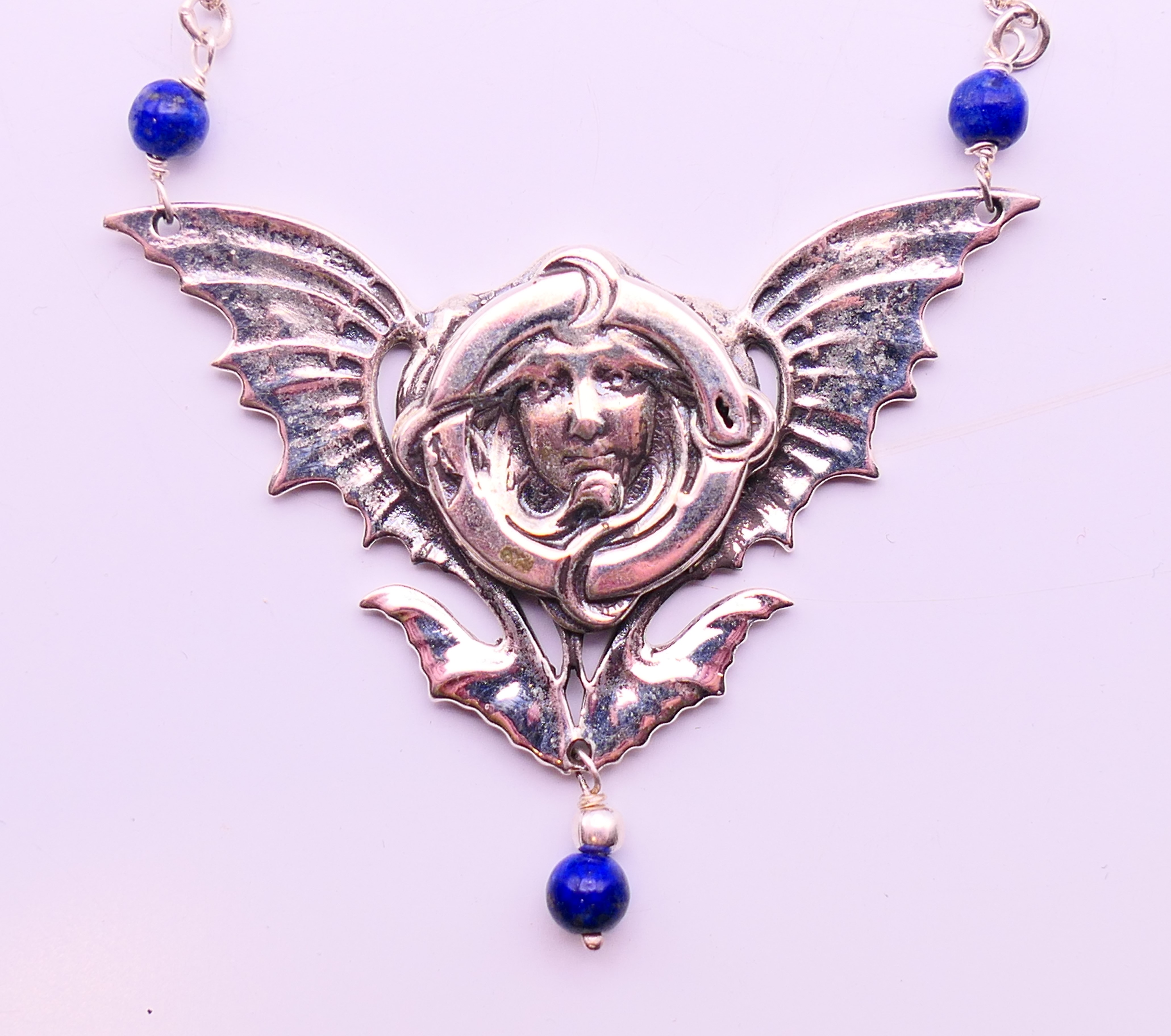 A silver Art Nouveau-style pendant necklace.