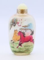 A snuff bottle and stopper depicting galloping horses, boxed. 8 cm high.