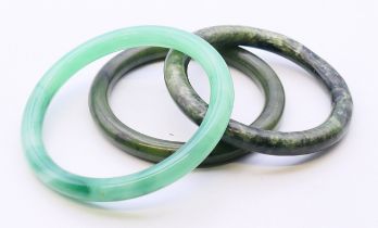 Three Chinese green jade bangles. Largest 6.5 cm internal diameter, 8 cm external diameter.