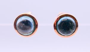 A pair of 9 ct rose gold earrings set with star cut/cabochon topaz gemstones. 0.5 cm diameter.