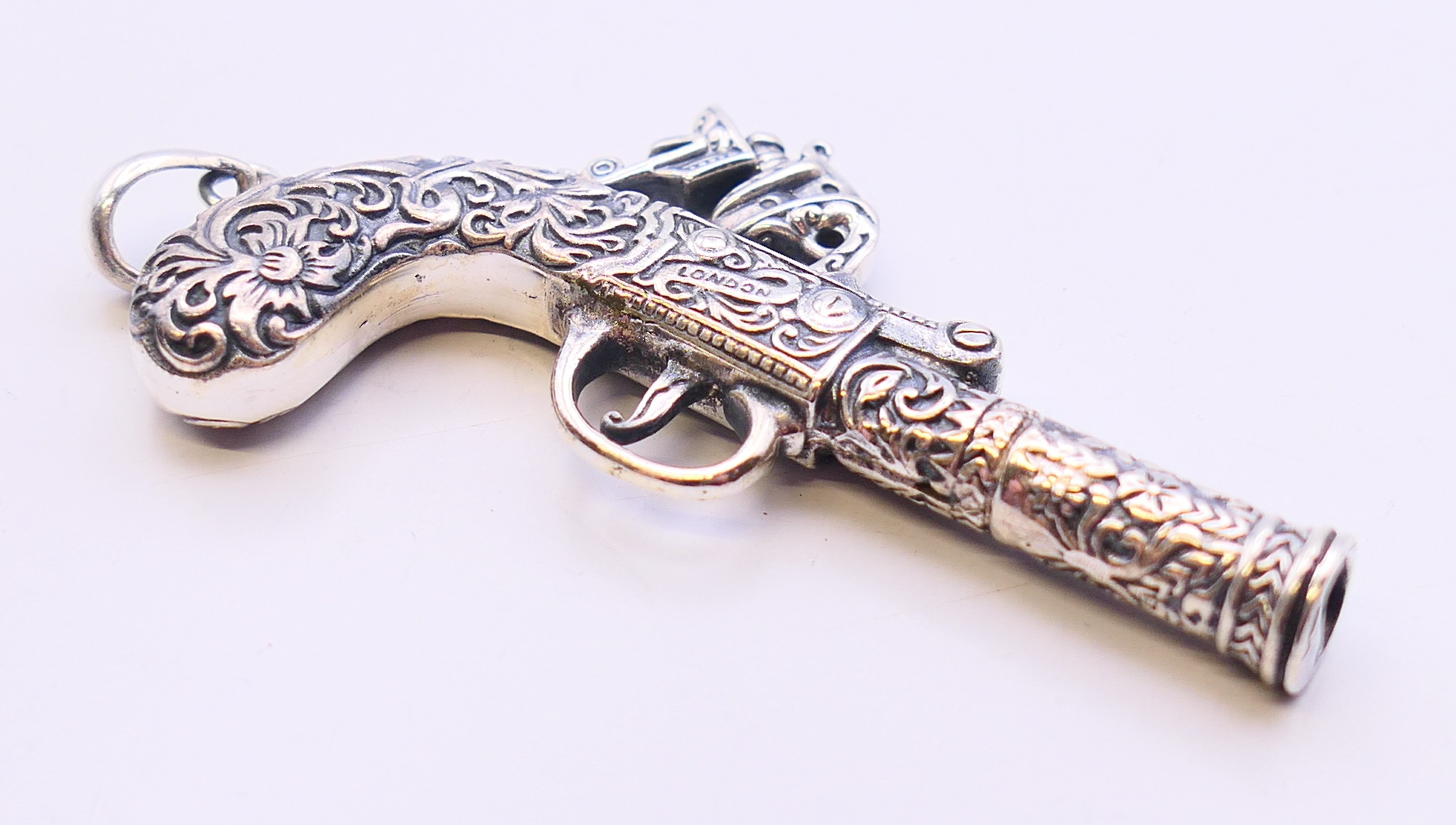 A silver pendant in the form of a pistol. 6.5 cm x 3.5 cm. - Image 2 of 3
