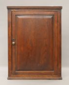 A George III elm hanging corner cupboard. 104 cm high, 77 cm wide.