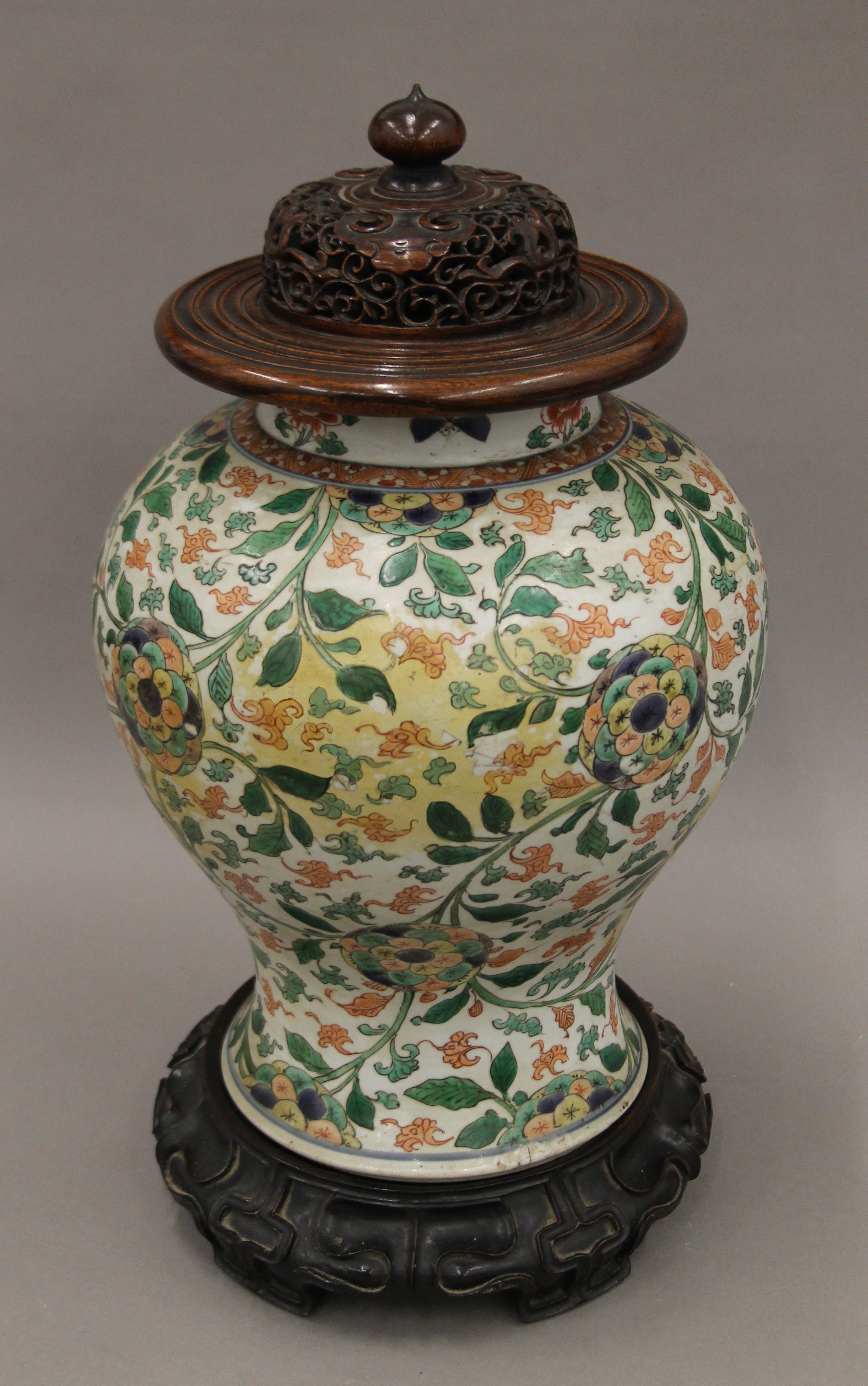A 18th/19th century Chinese porcelain vase with pierced wooden lid and carved wooden stand.