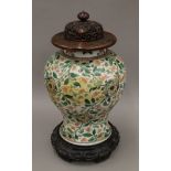 A 18th/19th century Chinese porcelain vase with pierced wooden lid and carved wooden stand.