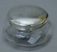 A glass dressing table jar with silver lid. 12.5 cm diameter. 43.1 grammes of silver.