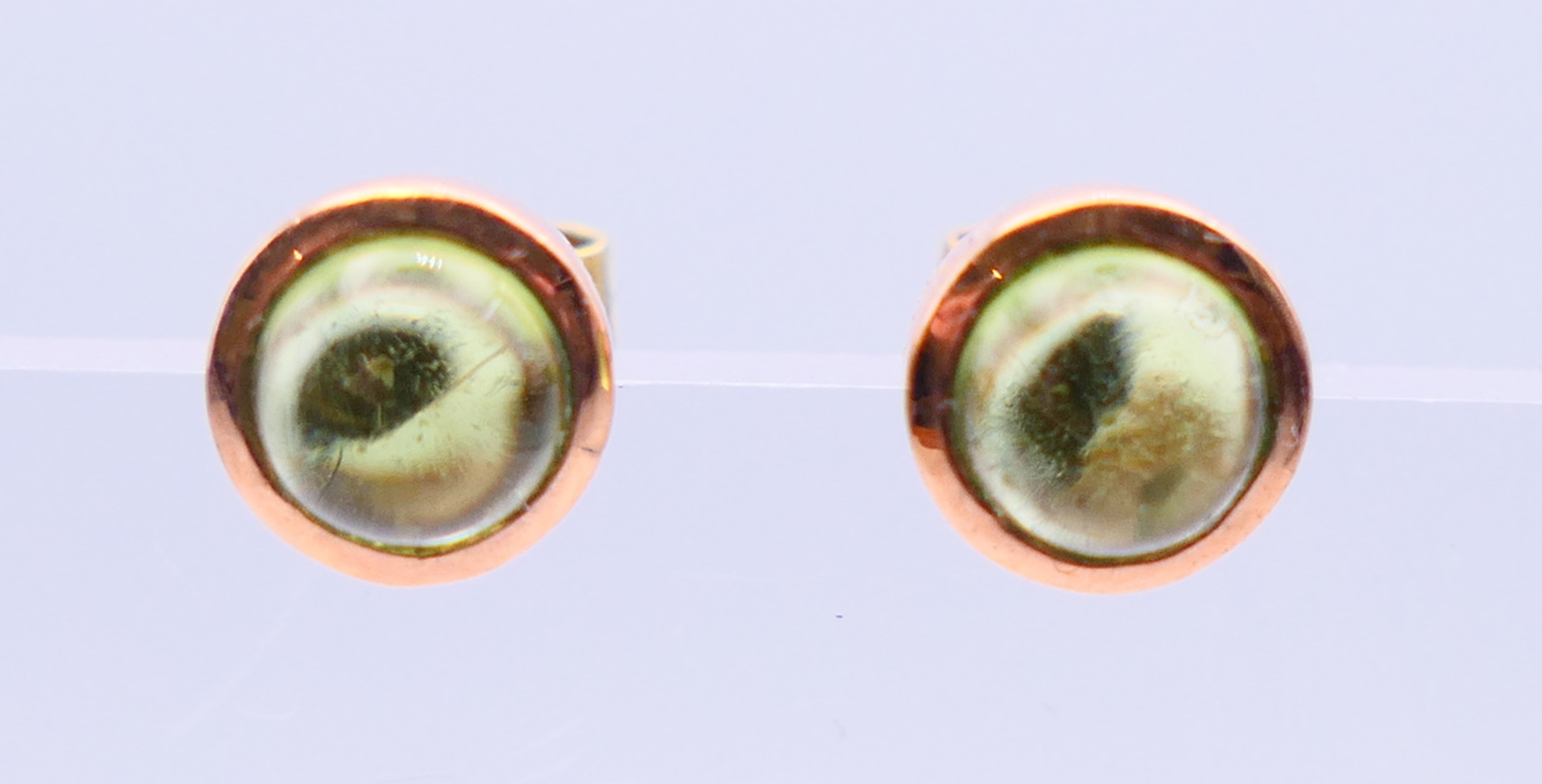 A pair of 9 ct rose gold earrings, each set with star cut/cabochon peridot gemstone. 0.