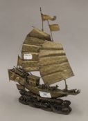 A Chinese white metal model of a junk on a carved wooden stand. 31 cm high.