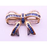 A 9 ct gold bow brooch set with mid-blue baguette sapphires and diamonds. 2.5 cm x 2 cm. 3.