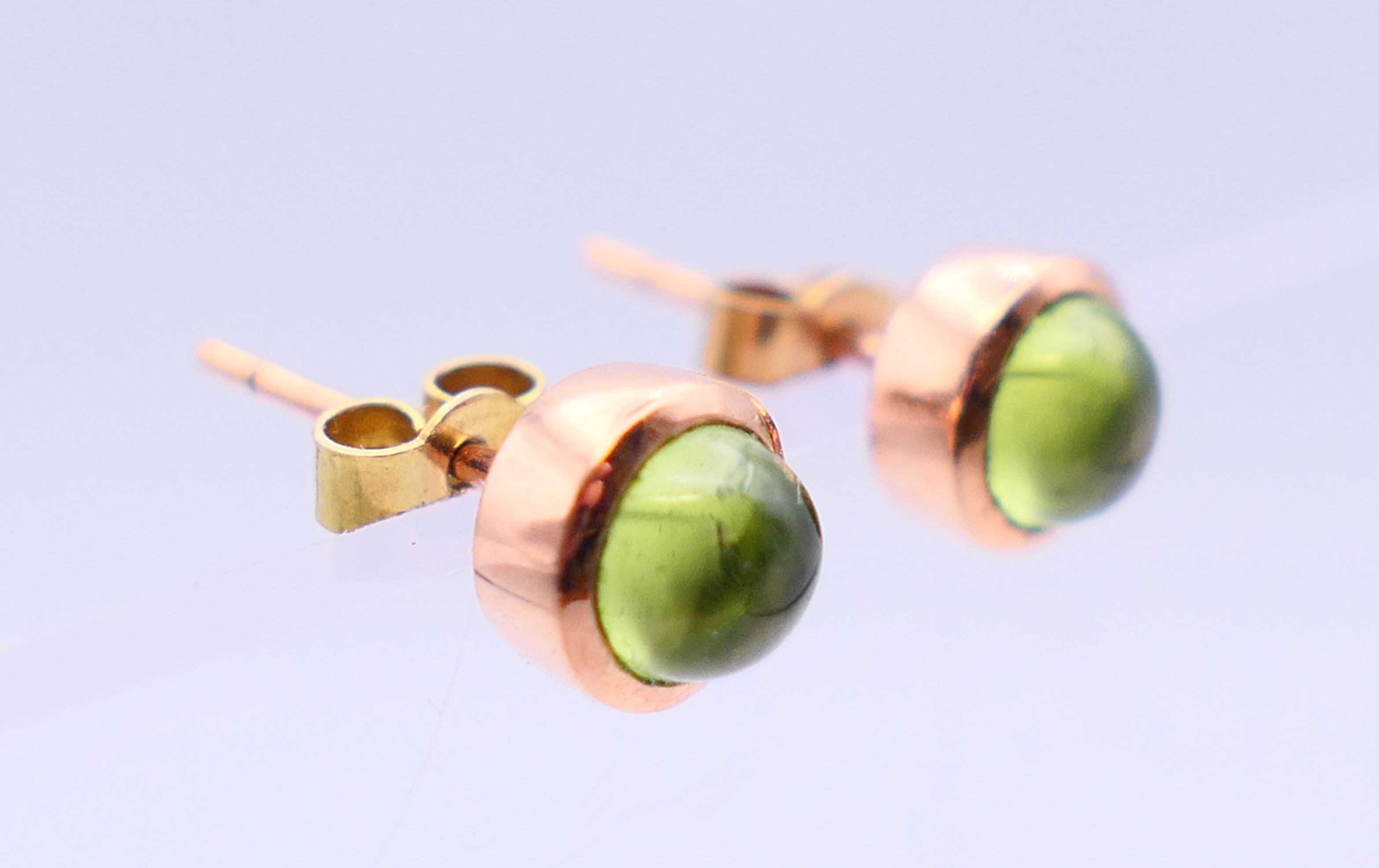 A pair of 9 ct rose gold earrings, each set with star cut/cabochon peridot gemstone. 0. - Image 3 of 5