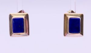 A pair of silver earrings set with polished lapiz lazuli. 1.25 cm x 1 cm.