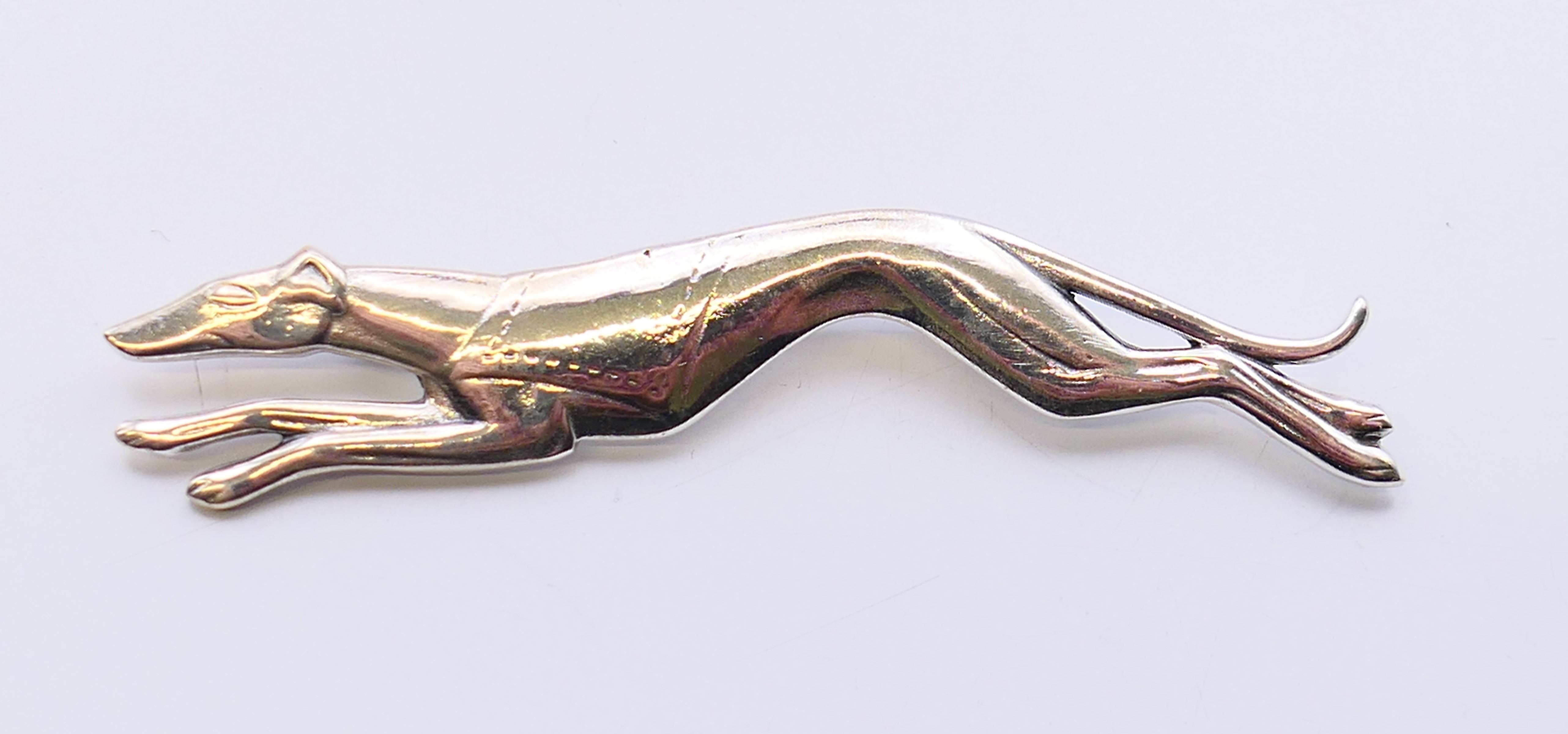 A silver brooch in the form of a greyhound. 7 cm long.