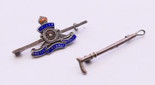 A silver brooch/tie pin in the form of a riding crop and a silver and enamelled Royal Artillery