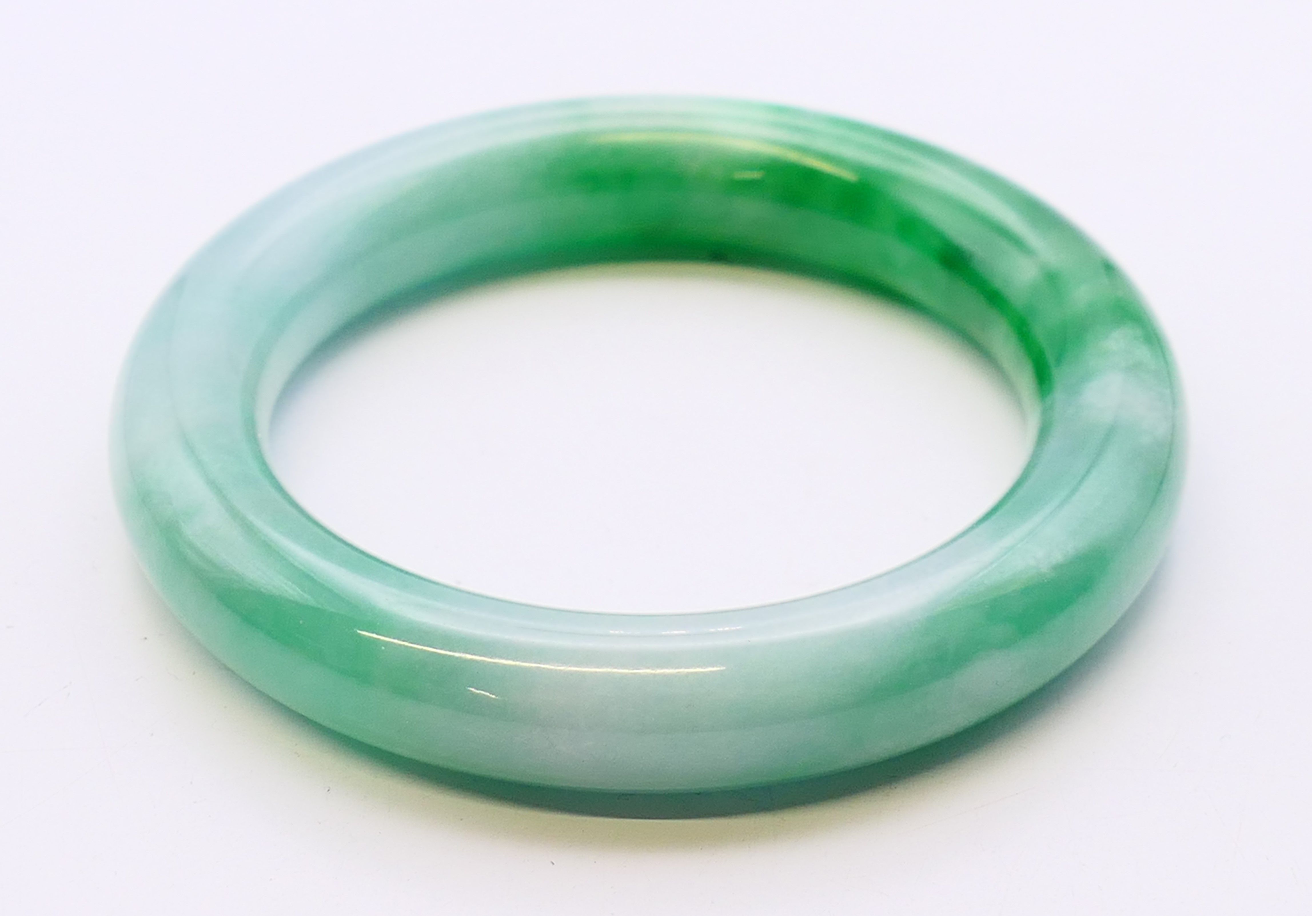 A two-tone jade bangle. 6 cm internal diameter, 8.5 cm external diameter.