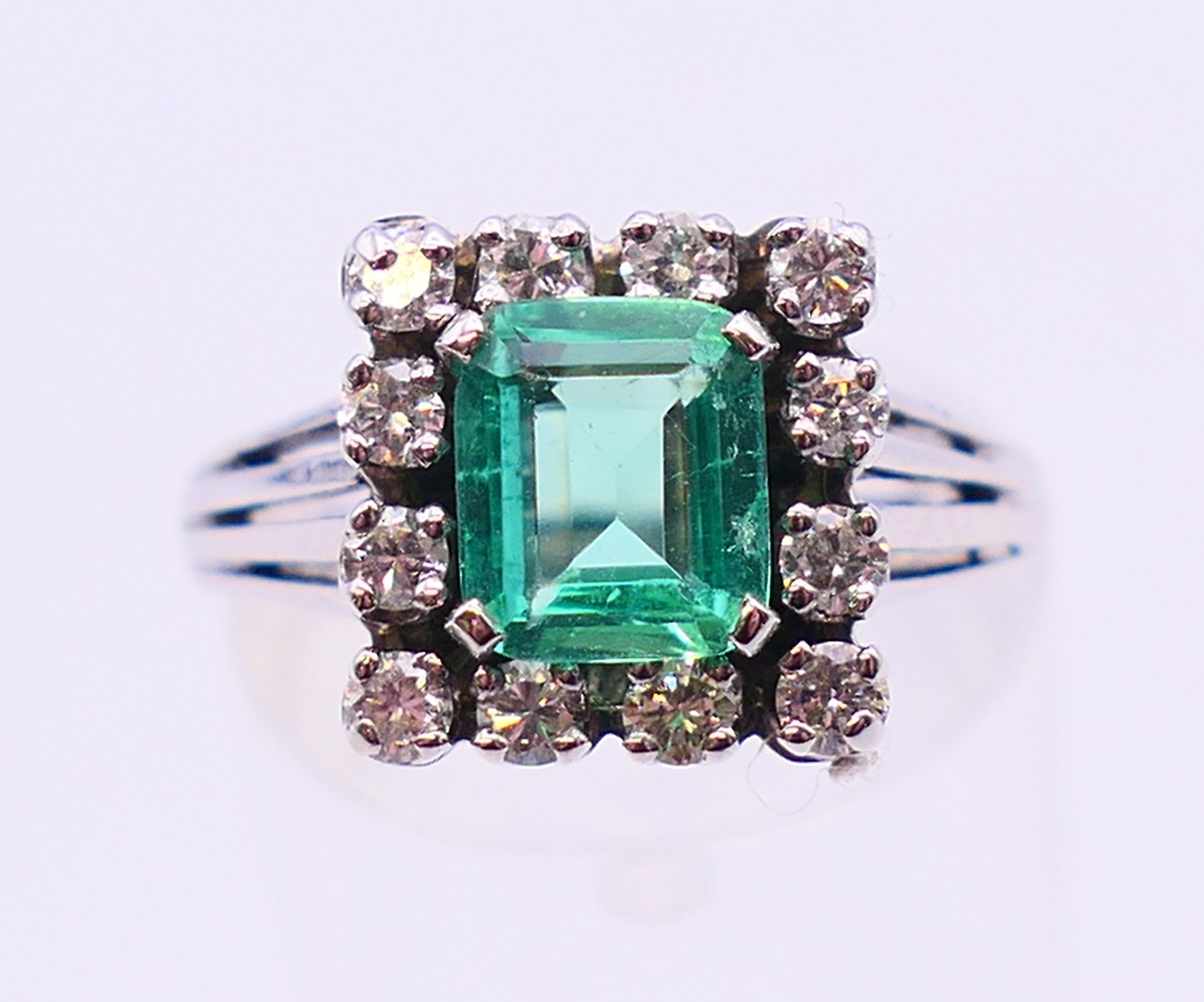 An unmarked 18 ct white gold, emerald and diamond ring. Ring size N/O.