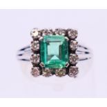 An unmarked 18 ct white gold, emerald and diamond ring. Ring size N/O.