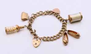 A 9 ct gold bracelet with padlock with five 9 ct gold charms. Approximately 18 cm long. 26.
