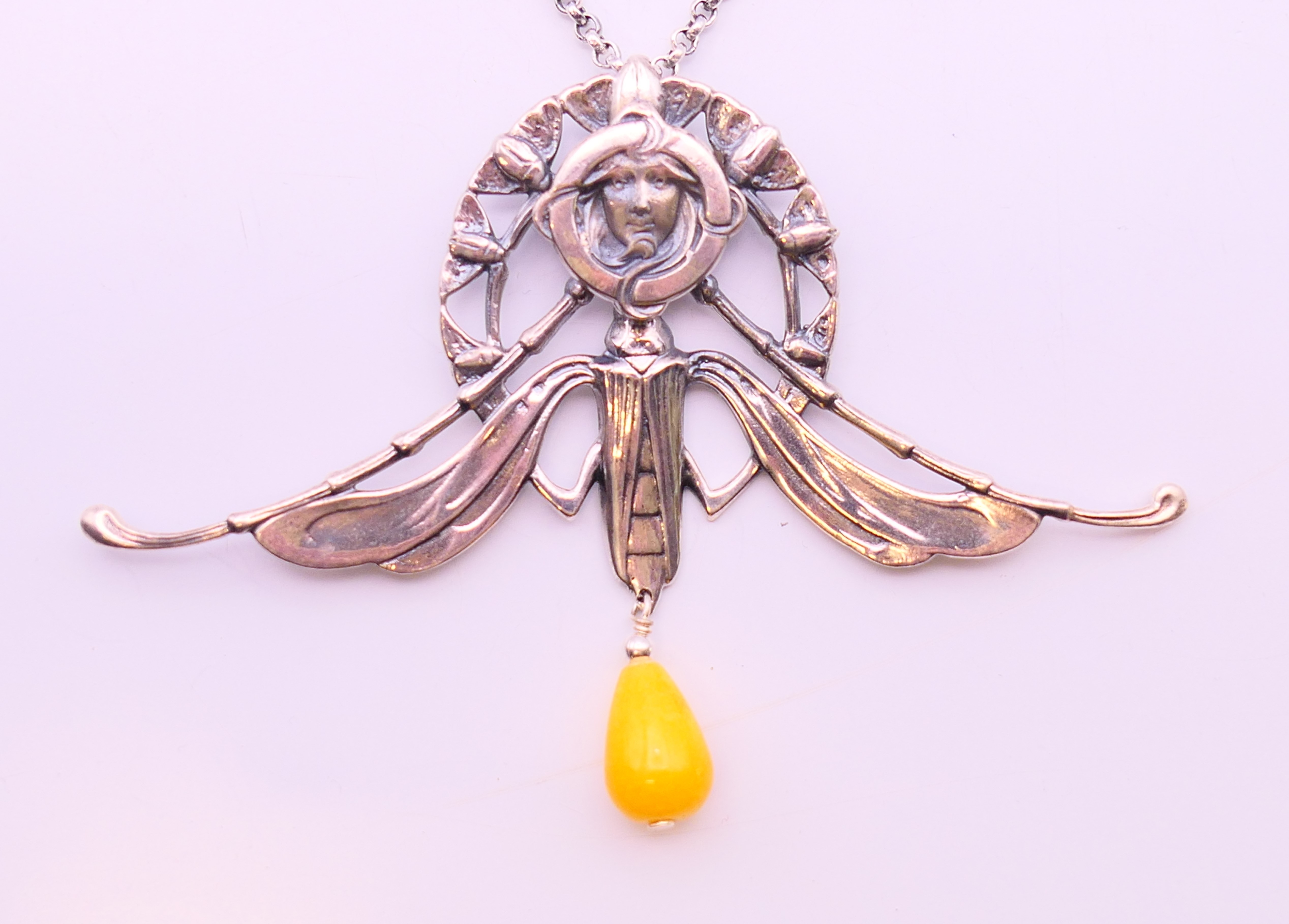 A silver Art Nouveau-style winged female head and bead pendant on a silver chain.