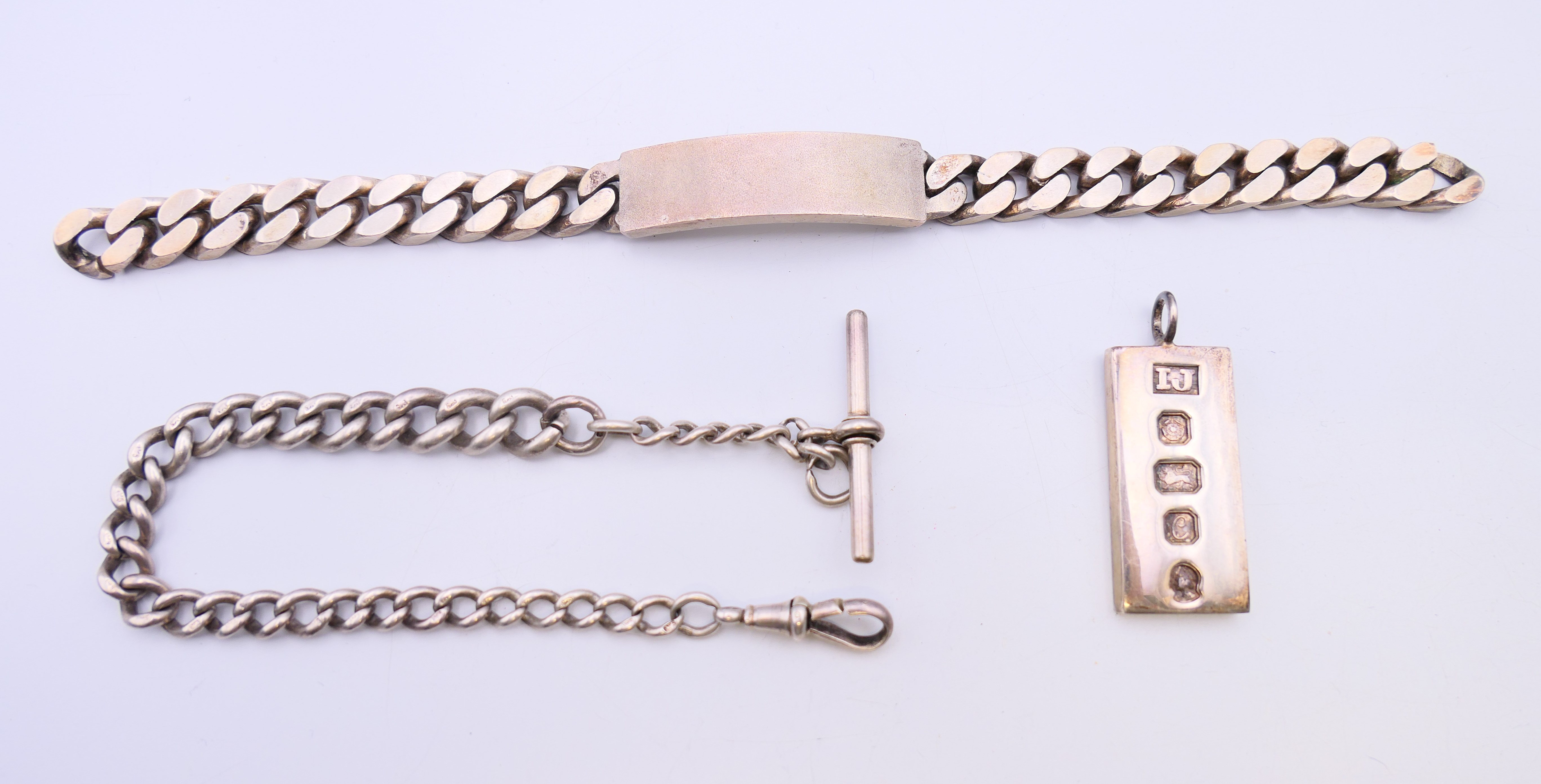 A silver ingot, an identity bracelet and a watch chain. Ingot 4 cm high. 130.1 grammes.