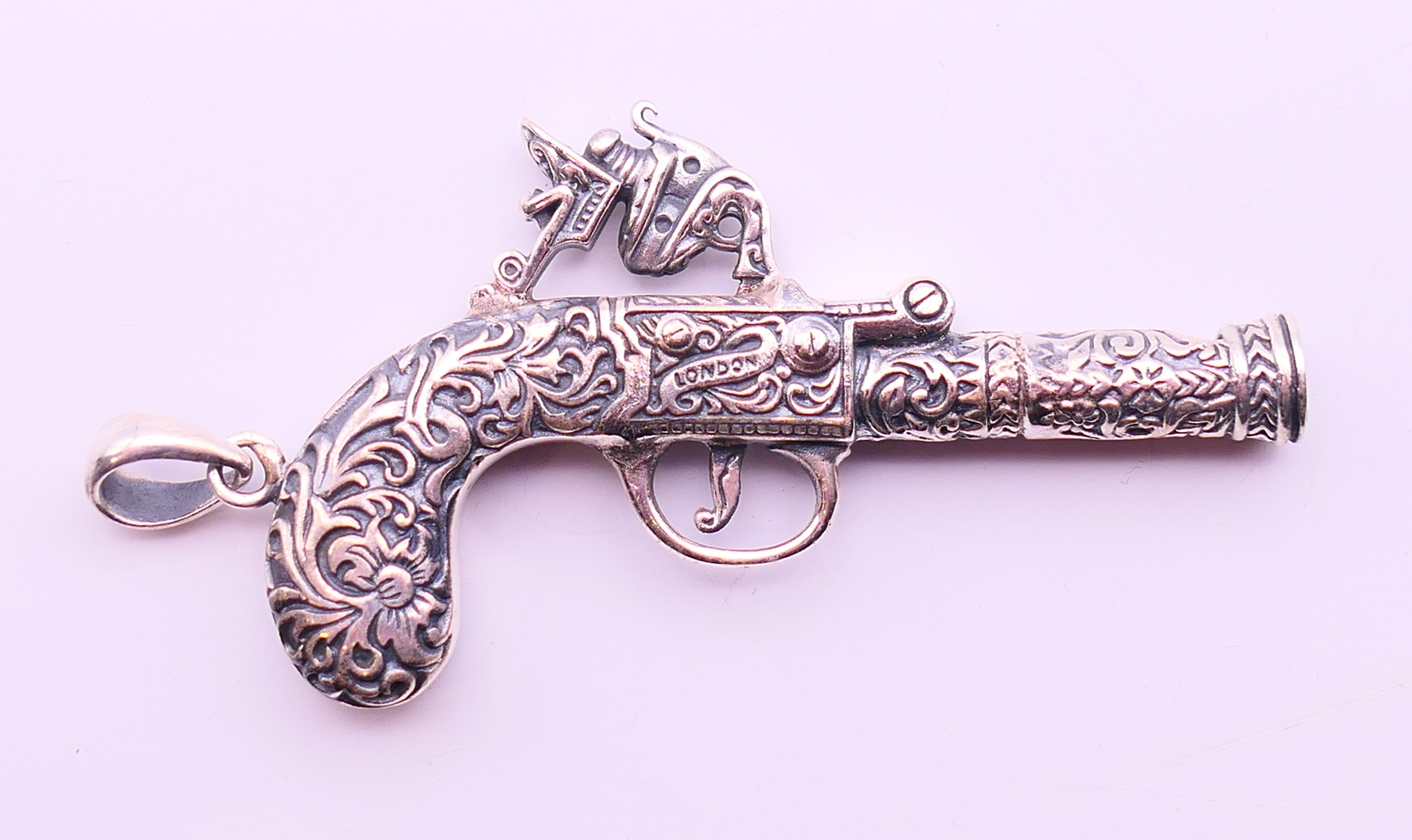 A silver pendant in the form of a pistol. 6.5 cm x 3.5 cm.