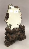 A Black Forest carved strutt mirror decorated with mountain goats. 35.5 cm high.