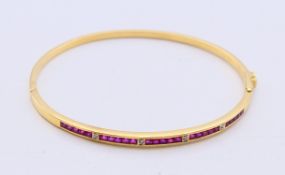 An 18 ct gold, ruby and diamond hinged bangle with twenty-five square shaped rubies (2mm),