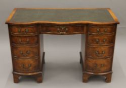 A mahogany serpentine-fronted pedestal desk. 115 cm long.