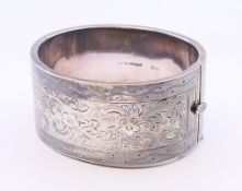 A chased silver bangle. 6.5 cm external diameter.