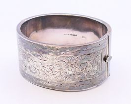 A chased silver bangle. 6.5 cm external diameter.