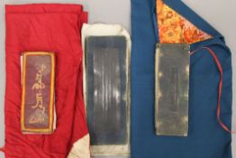 Three antique Tibetan Buddhist prayer texts in protective cloth wrappings. The largest 30 cm high.