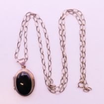 A silver onyx locket with a chain, both stamped 925. Locket 3 cm high, chain 54 cm long.